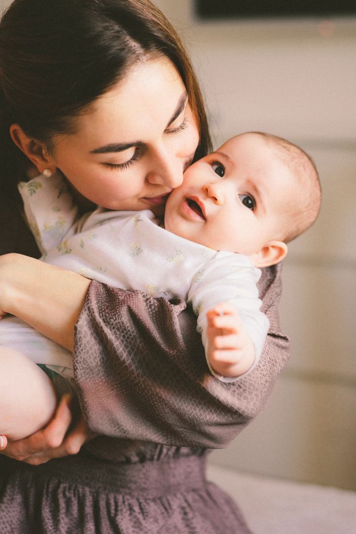 A mother lovingly embraces her smiling baby testing by DNA Test Solutions.
