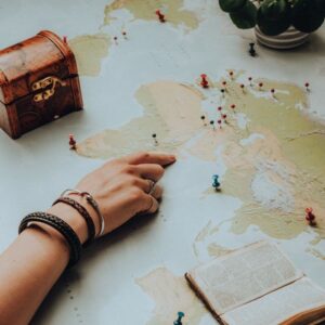Hand pointing on a world map surrounded by travel essentials, sparking a sense of adventure.
