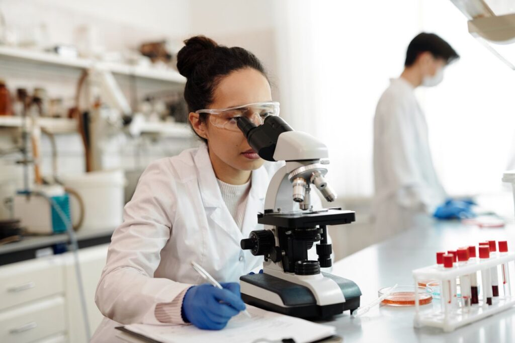 A scientist in a lab coat using a microscope in a modern laboratory setting of DNA Forensics Test Solutions PVT LTD.