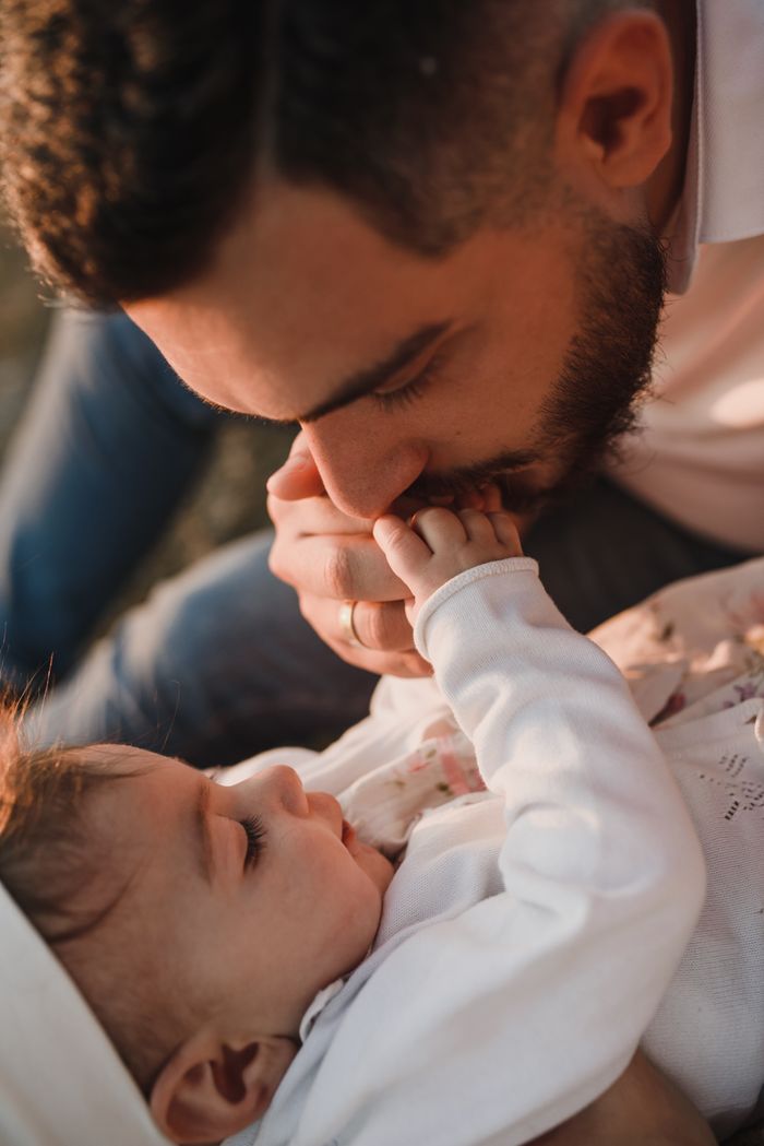 Touching moment of a father kissing his baby's hand, symbolizing love and parenthood at the time of DNA testing by DNA Forensics Test Solutions