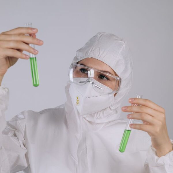 Scientist examines green liquid in test tubes with protective gear on, cell line authentication by Evidexa DNA Test Solution