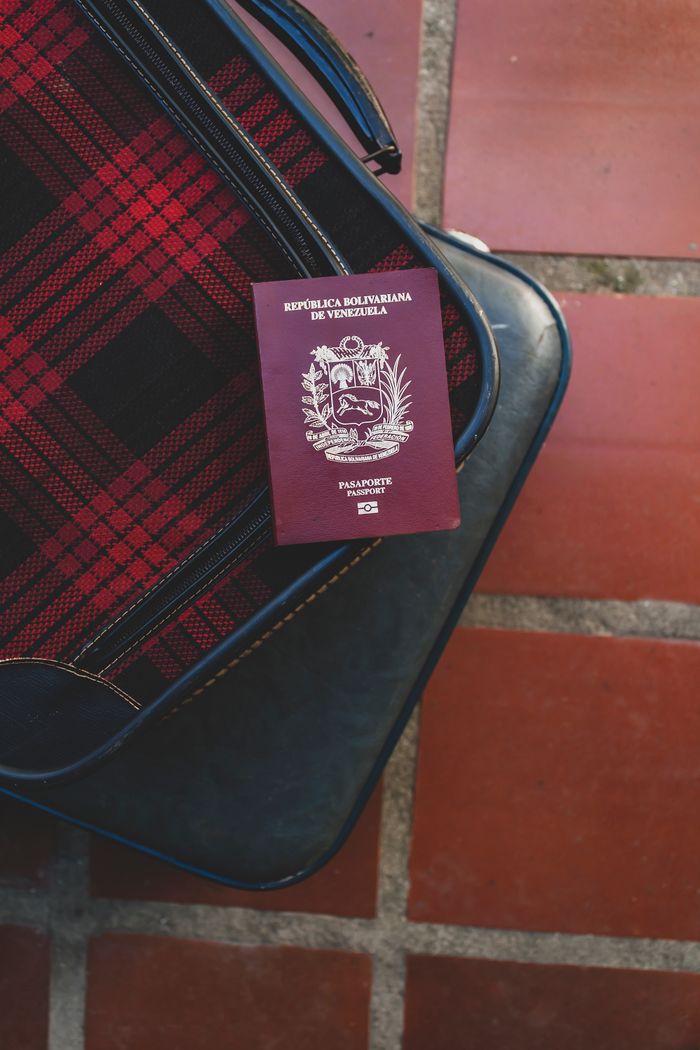 Close-up of Venezuelan passport atop plaid suitcase on tiled floor at DNA Test Solutions
