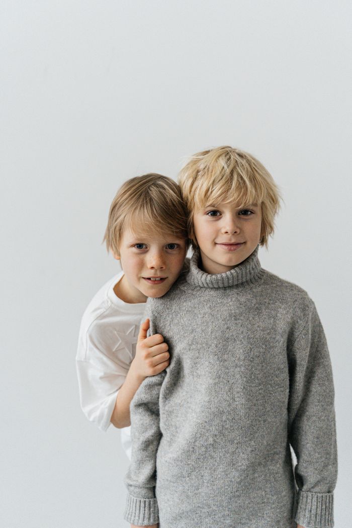 Charming portrait of two smiling boys wearing cozy sweaters against a soft white background ready for DNA Test by DNA Test Solutions