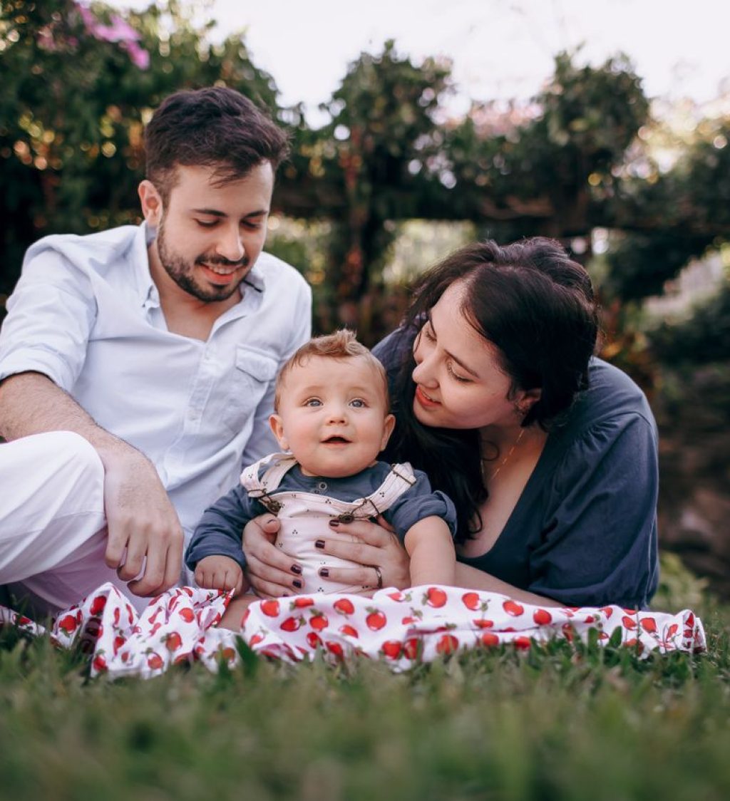 A young family with a baby enjoys a relaxing outdoor picnic on a warm sunny day, surrounded by nature.